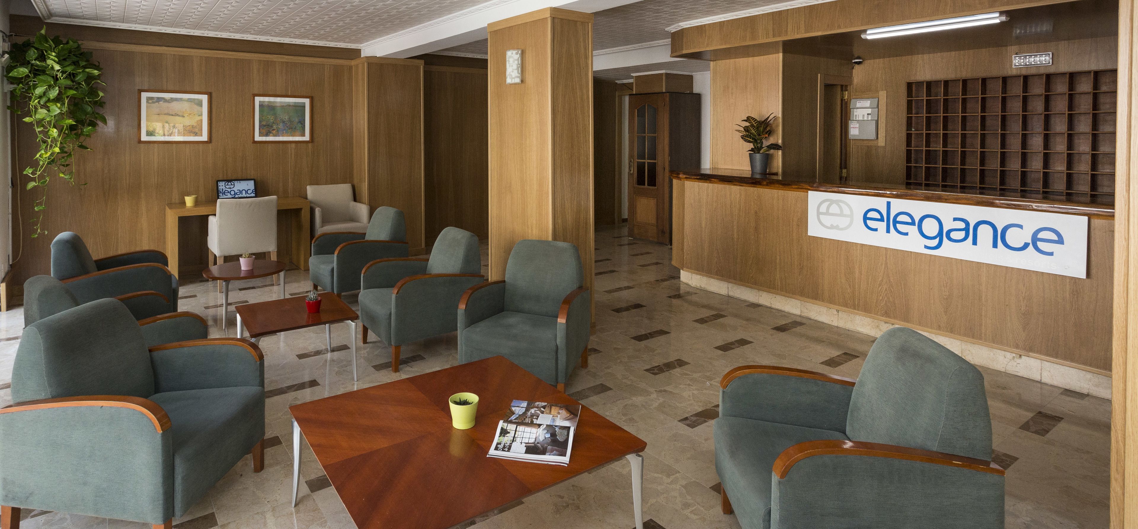 Un área de recepción con un mostrador de madera, varias opciones de asiento y un cartel que dice "elegance".