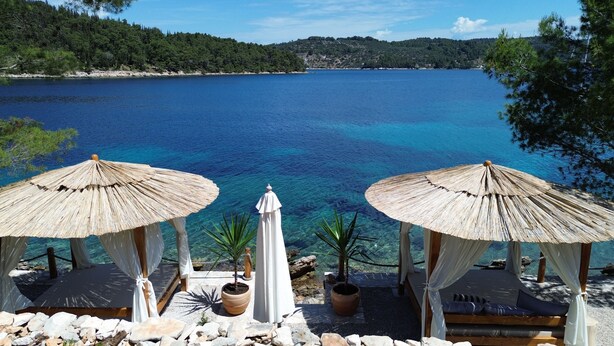 A seaside view with two thatched umbrellas and lounge chairs overlooking a clear blue sea. - Eco Pebble Bay Beach House (Vela Luka)