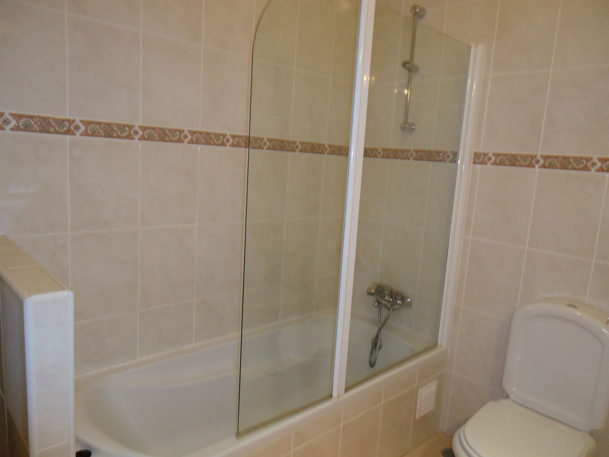 Un baño con ducha de vidrio, bañera y retrete.