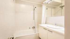 A modern bathroom with a bathtub, a shower, a sink, and a mirror with lights. - Gaston Lejeune 304 (Koksijde)