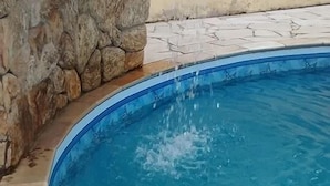 En swimmingpool med en stenvæg og et vandfald.