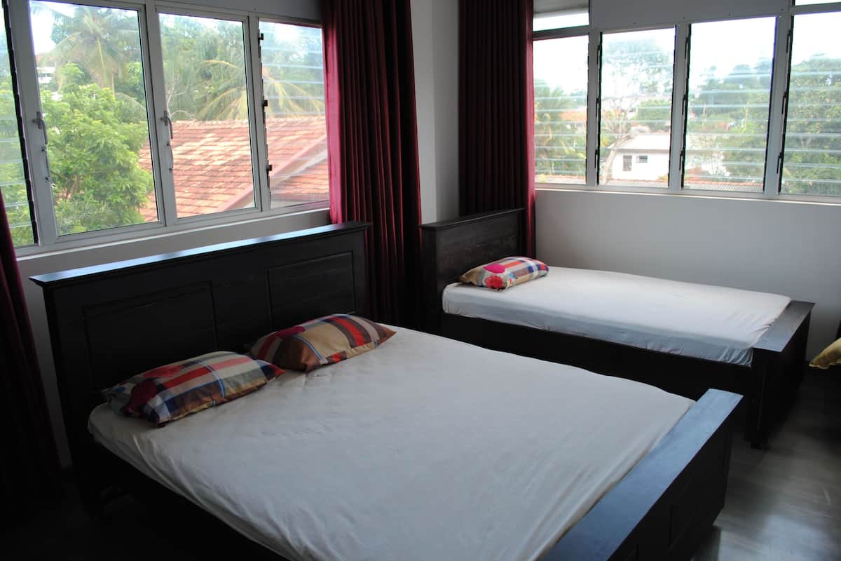 A hotel room with two beds, large windows, and curtains.