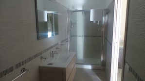 Un baño con ducha, lavamanos y espejo.