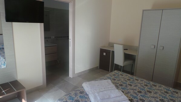 Un dormitorio con cama, escritorio, armario y baño.