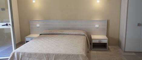 A bedroom with a bed, bedside tables, a wardrobe, and wall-mounted lights.