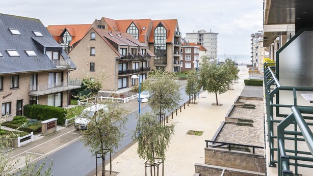 A residential area with a mix of modern and traditional architecture, featuring a variety of building styles and a tree-lined street. - Pablo II-301 (Koksijde)