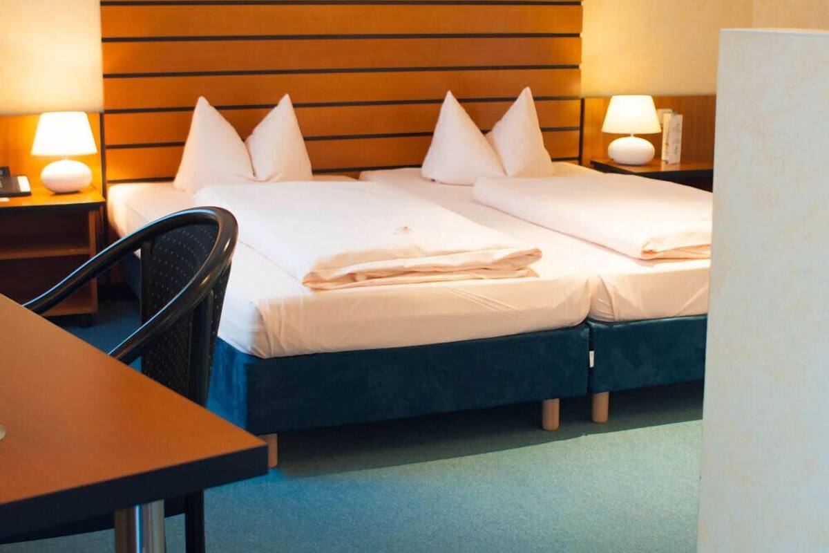 Ein Hotelzimmer mit Doppelbett, zwei Nachttischen mit Lampen, einem Sessel und einem Schreibtisch.