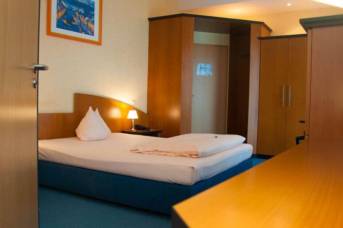 Ein Hotelzimmer mit einem Bett, einer Nachttischlampe und einem Holzschrank.