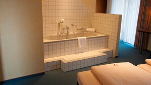 Une chambre d’hôtel avec une baignoire, un lit et une fenêtre avec des rideaux.