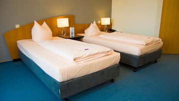 Two twin beds with headboards, bedside lamps, and a blue carpeted floor.