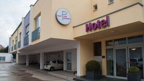 Un hôtel avec une enseigne indiquant « Hôtel Stadt Püttlingen » et un parking souterrain où sont garées plusieurs voitures.