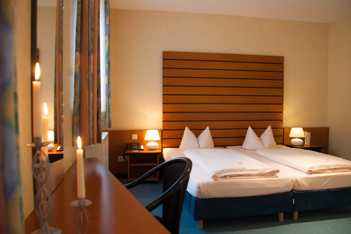 Ein Hotelzimmer mit einem Doppelbett, Nachttischen mit Lampen, einem Sessel und einem Holzkopfstück.