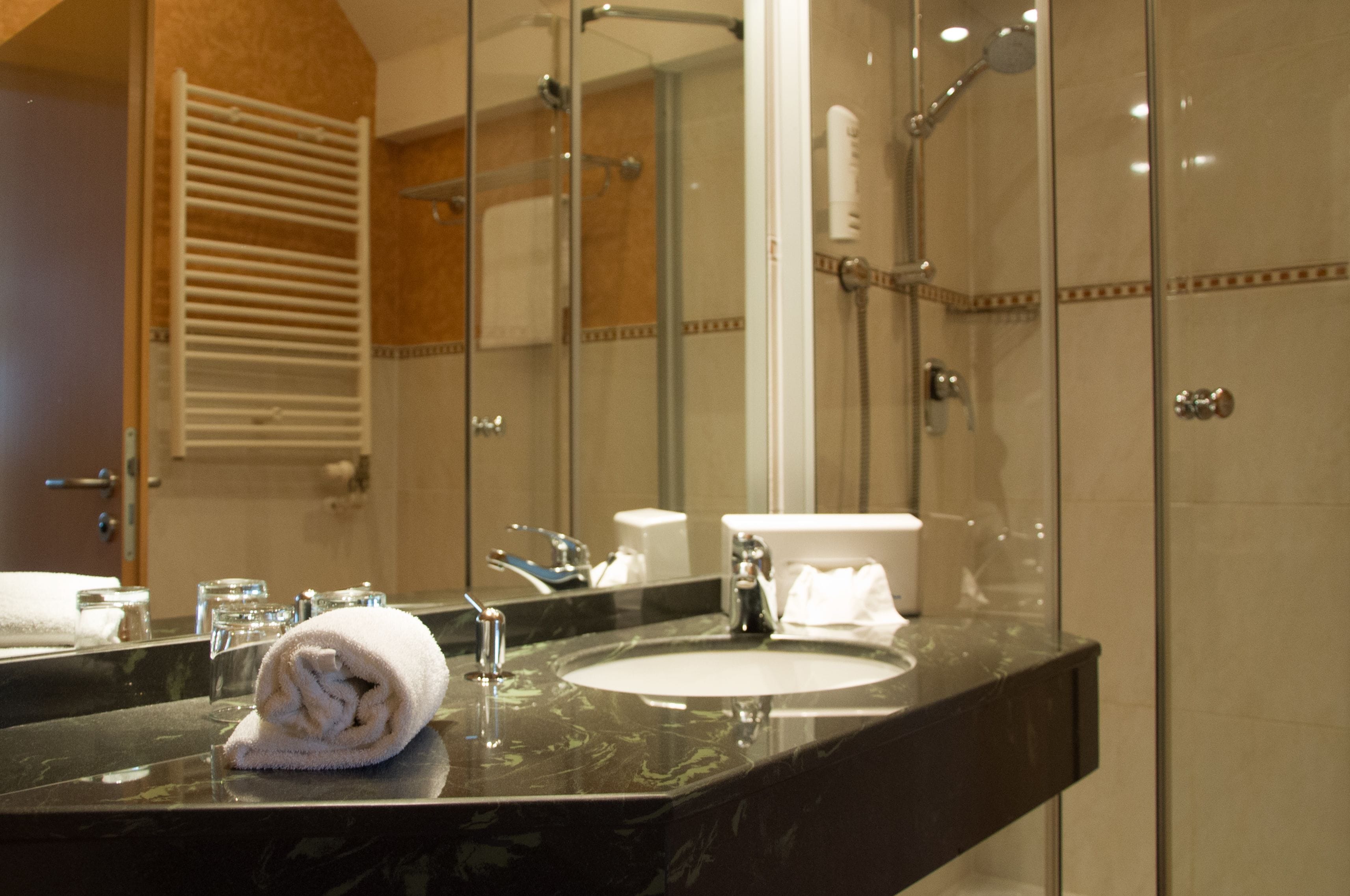 A bathroom with a marble sink, a glass shower enclosure, and a towel rack.