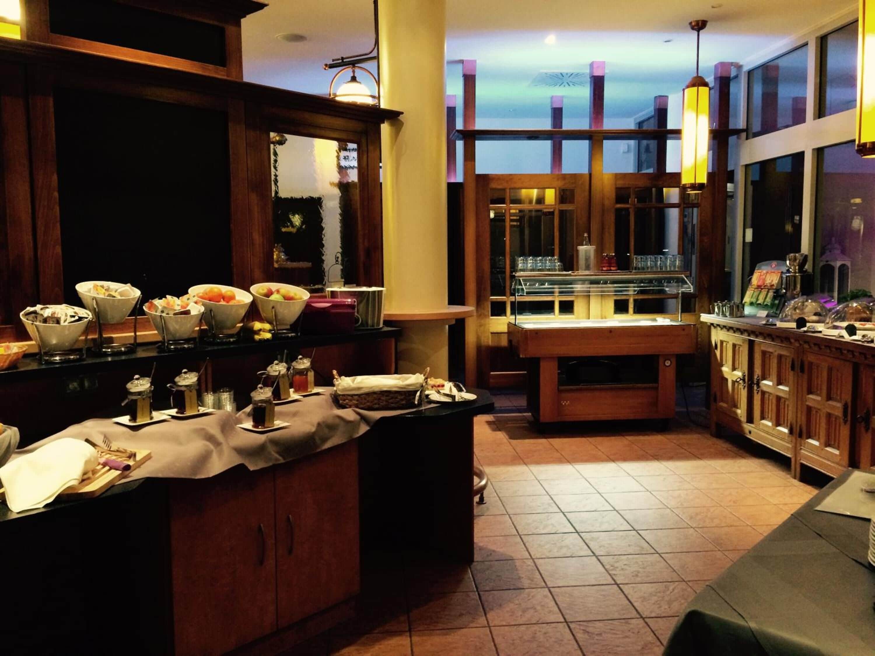 A well-lit breakfast bar with various food items and condiments, wooden cabinets, and a large window offering a view of the sky.