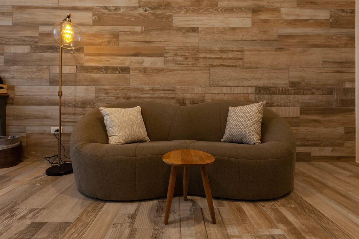 A modern living room with a curved sofa, a small wooden side table, and a floor lamp.