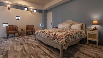 Ein Schlafzimmer mit einem großen Bett, zwei Sesseln, einem kleinen Tisch und einem Nachttisch.