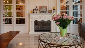 A living room with a fireplace, a glass coffee table, and a vase of flowers. - Rambling Snail (Luodong)