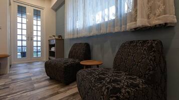 A room with two patterned armchairs, a small wooden table, and a bookshelf.