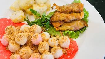Une assiette contenant divers aliments, notamment des pommes de terre, du poisson frit et une salade composée de laitue et de différentes garnitures.