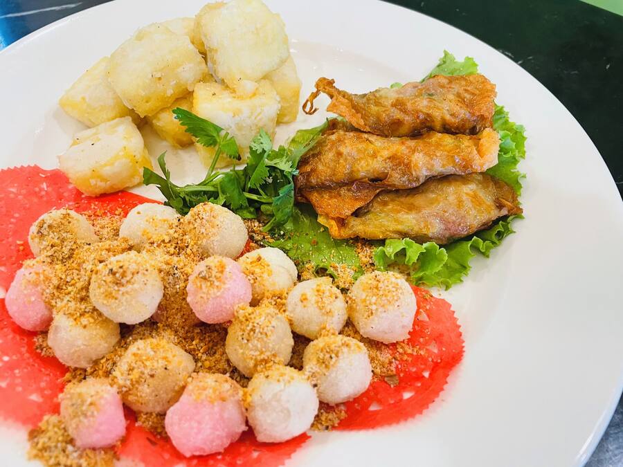 Une assiette contenant divers aliments, notamment des pommes de terre, du poisson frit et une salade composée de laitue et de différentes garnitures.