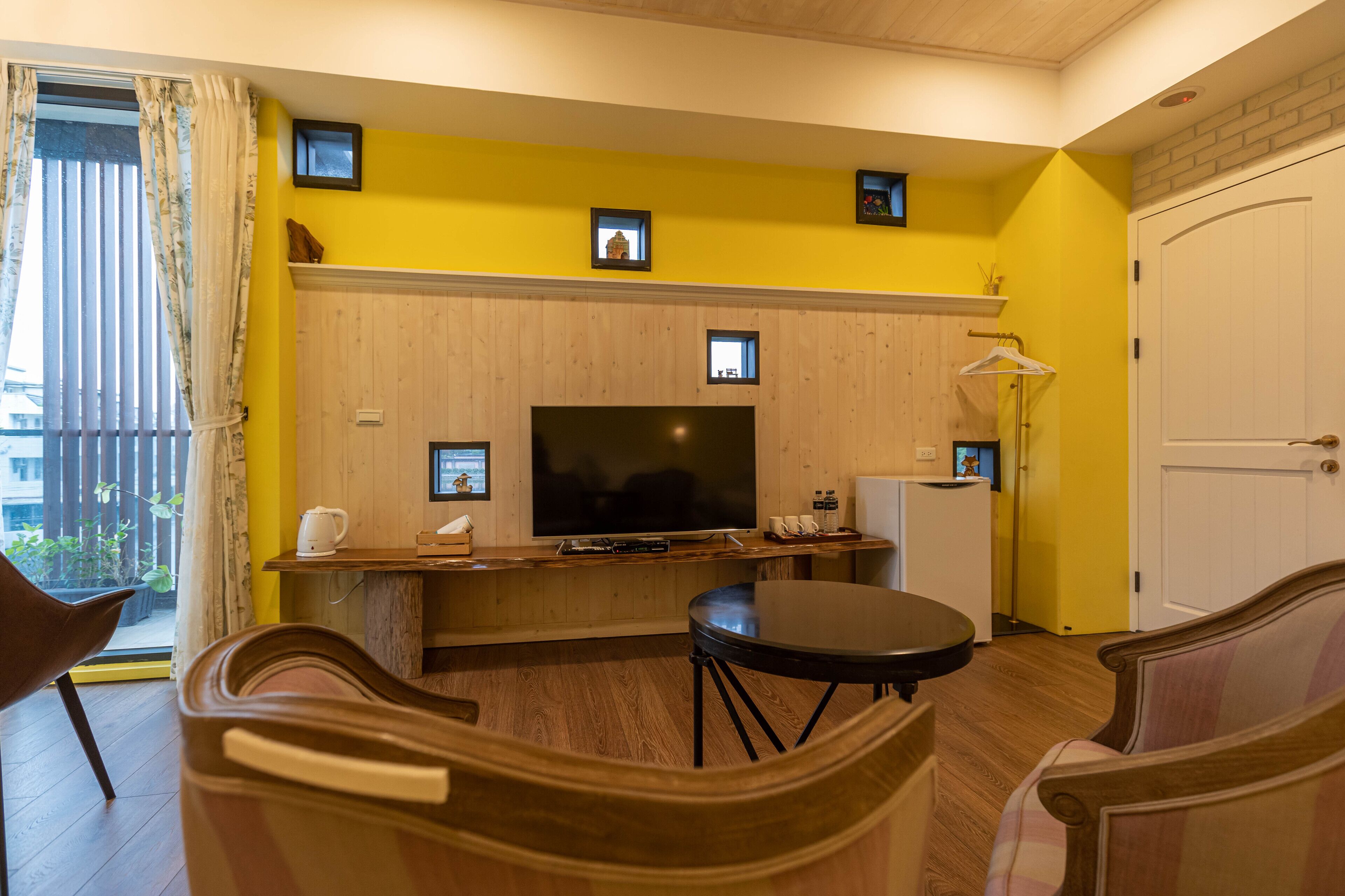 Una sala de estar con televisor, muebles de madera y pared amarilla.