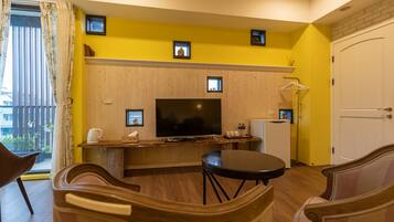 Una sala de estar con televisor, muebles de madera y pared amarilla.