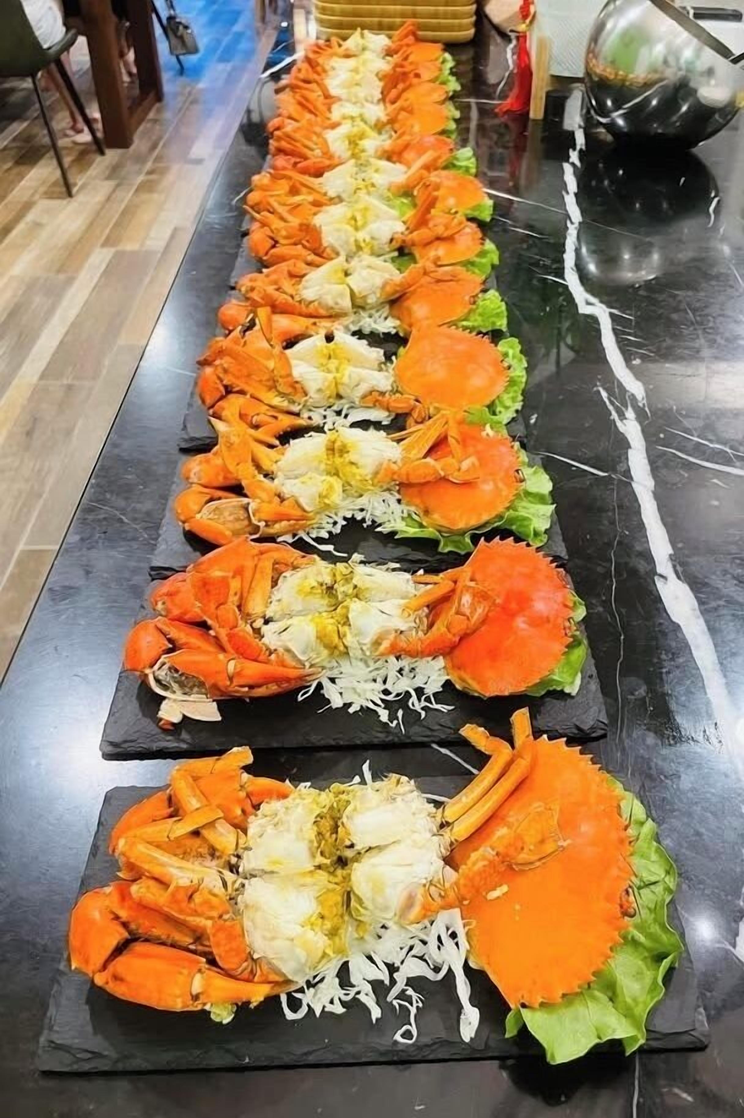 A long table with neatly arranged crab legs and greens.