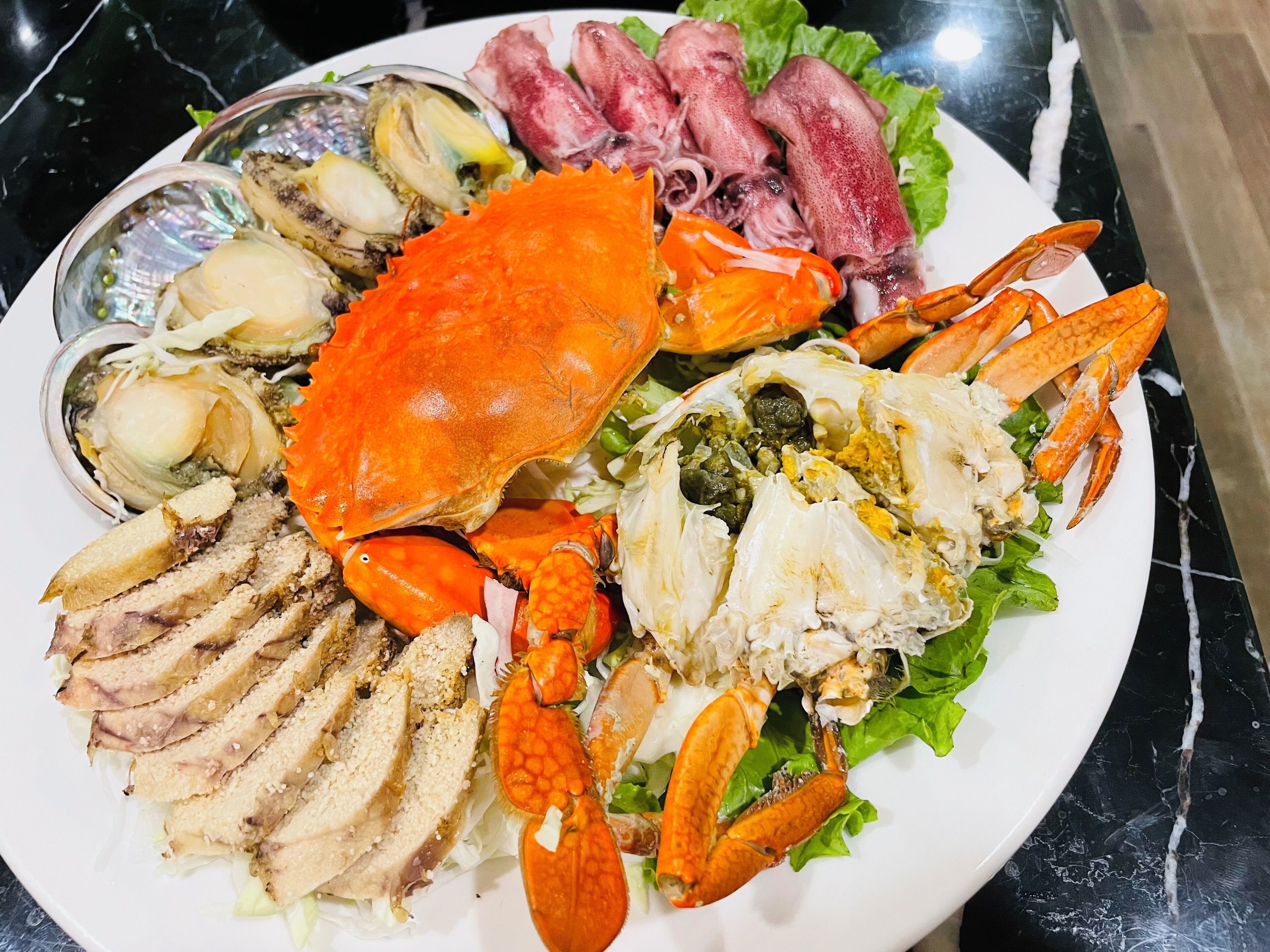 Un piatto di pesce con granchi, ostriche e altri frutti di mare.