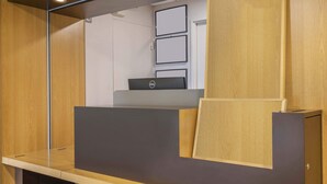 Un mostrador de recepción con una computadora portátil, paneles de madera y cuadros en la pared.