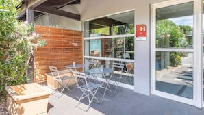 Un patio al aire libre con una mesa, sillas, un cerco de madera y una puerta de cristal con un letrero.