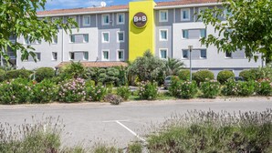Un hotel tipo casa huéspedes con un letrero amarillo, varias ventanas y un estacionamiento.