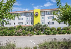 Un hôtel de type « bed and breakfast » avec une enseigne jaune, de nombreuses fenêtres et un parking.