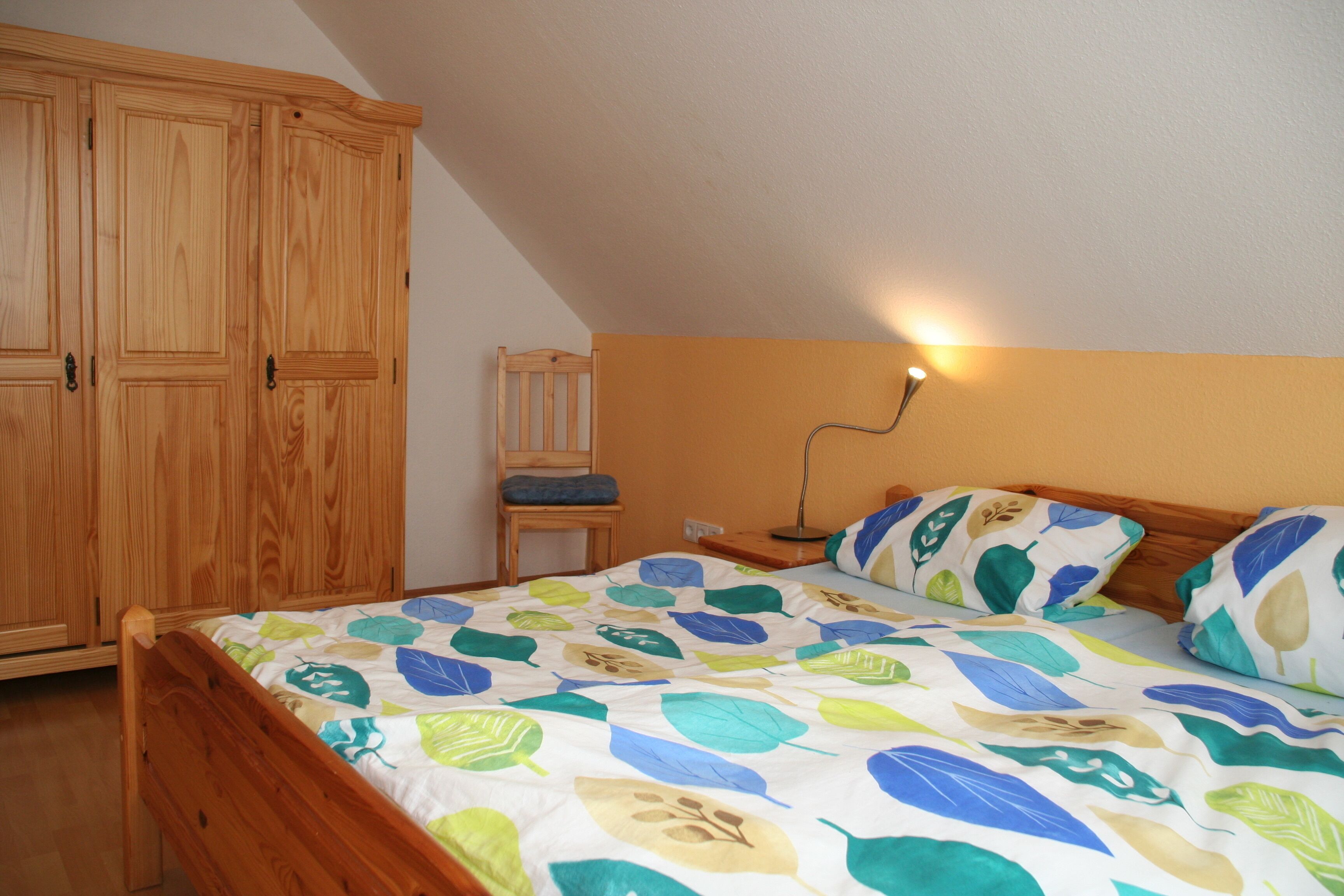 Una camera da letto con un letto di legno, un comodino, una lampada e un armadio.