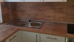 A kitchen with white cabinets, a stainless steel sink, and a wooden countertop.