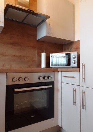 Kitchen area with stainless steel oven, microwave, and white cabinets.