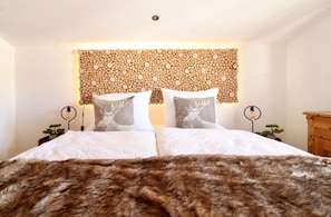 A bed with a fur throw, two bedside tables with lamps, and a wall with a circular pattern.