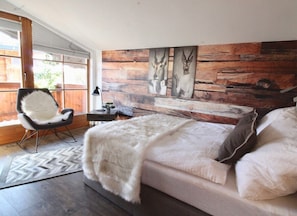 Une chambre moderne avec un grand lit, une chaise, un bureau et un mur orné de panneaux en bois et de motifs animaliers.