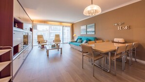 Una sala de estar moderna con comedor, sofá, mesa de centro y televisor.