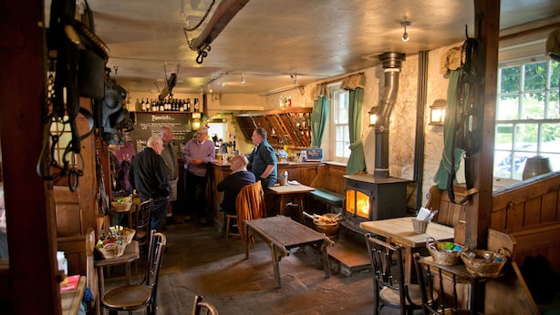 A rustic pub with wooden furniture, a fireplace, and a stone floor. - Monsal Head Hotel (Buxton)