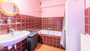 Un baño con lavamanos, espejo, bañera y cortina de ducha.
