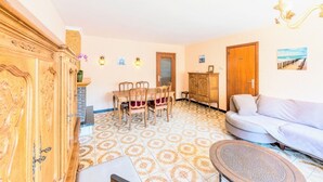 Un salón con una mesa de comedor, sofá y baldosas estampadas en el suelo.