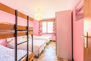 A room with bunk beds, a radiator, a window with curtains, and a door with a handle. - Wind en Zee 301 (Koksijde)