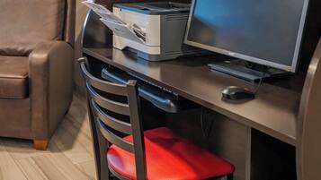 Un espacio de trabajo con escritorio, computadora, impresora y una silla roja.