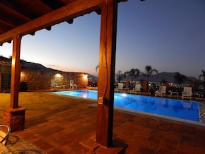A swimming pool with lounge chairs and a stone wall in the background. - B&B Sole e Luna (Palermo)