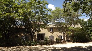 A rustic building with a stone facade, multiple windows, and lush greenery surrounding it. - La Bastide B&B (Cavaillon)