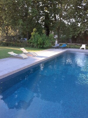 Una piscina al aire libre, tumbonas