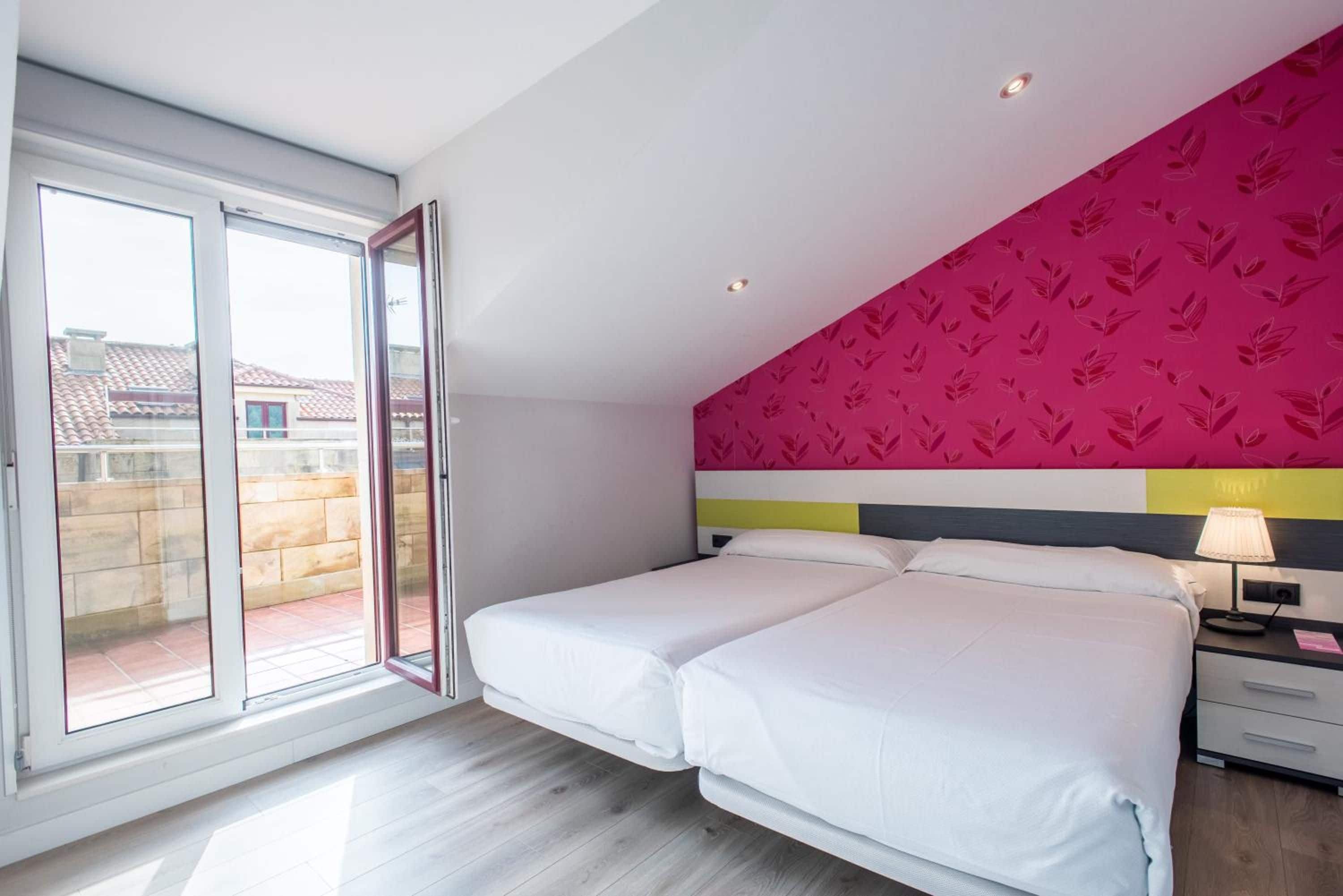 A hotel room with a bed, a nightstand, a lamp, and a view through a sliding door.