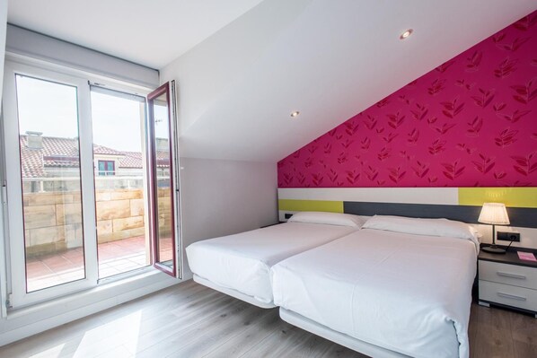 A hotel room with a bed, a nightstand, a lamp, and a view through a sliding door. - Apartamentos La Albarca (Entrambasaguas)