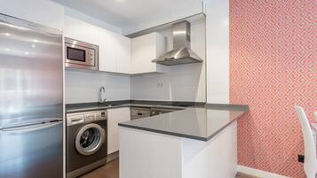 A modern kitchen with stainless steel appliances, a built-in washing machine, and a patterned wall.