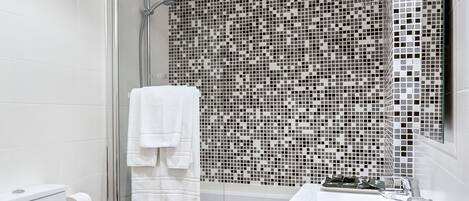 Un baño moderno con cabina de ducha de vidrio, inodoro blanco y tocador negro.